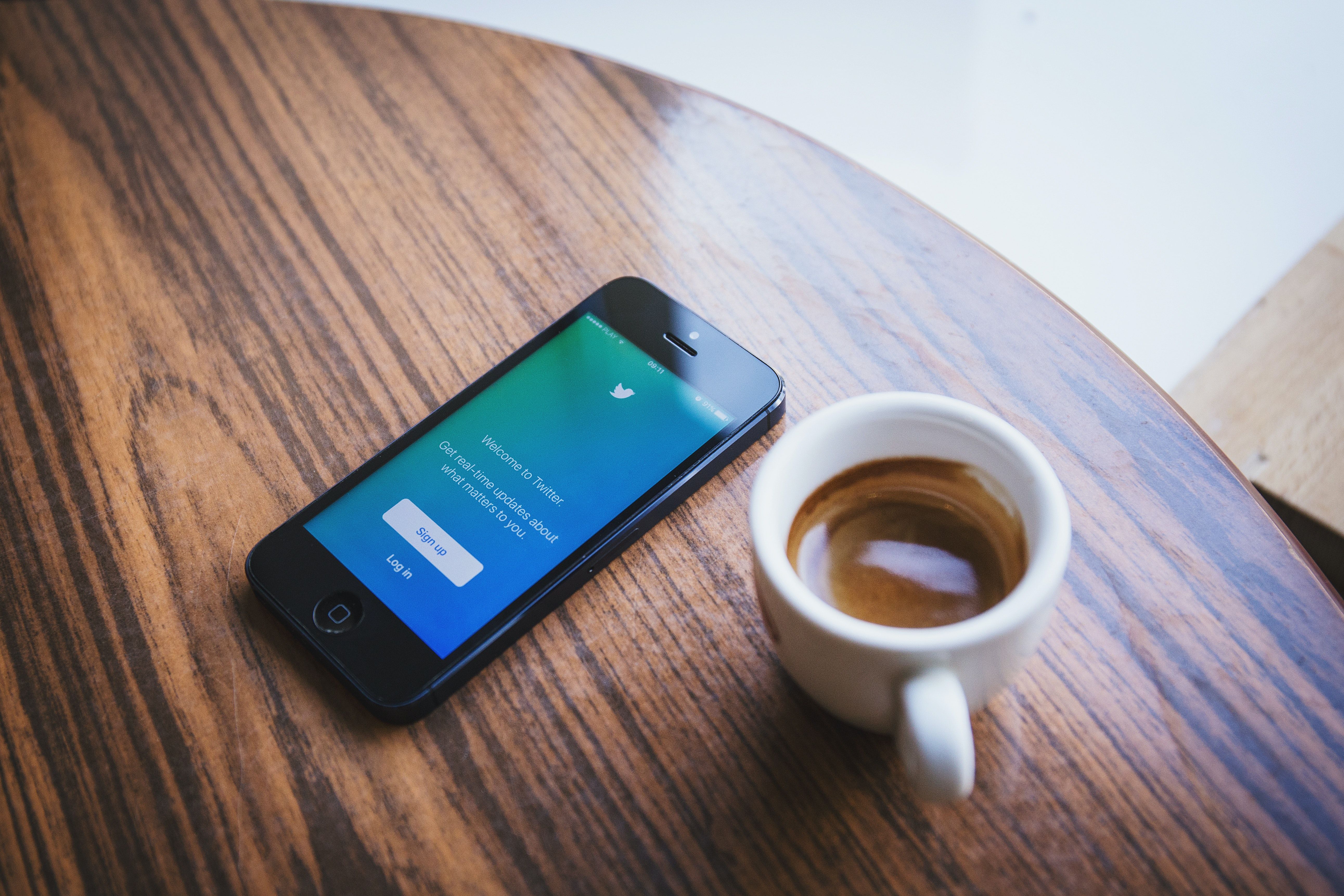 Un móvil con Twitter abierto y un vaso de café / PEXELS