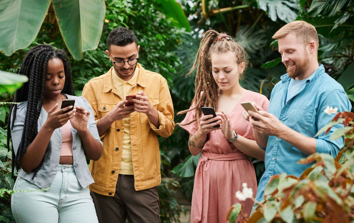 Cuatro personas con sus teléfonos móviles / PEXELS