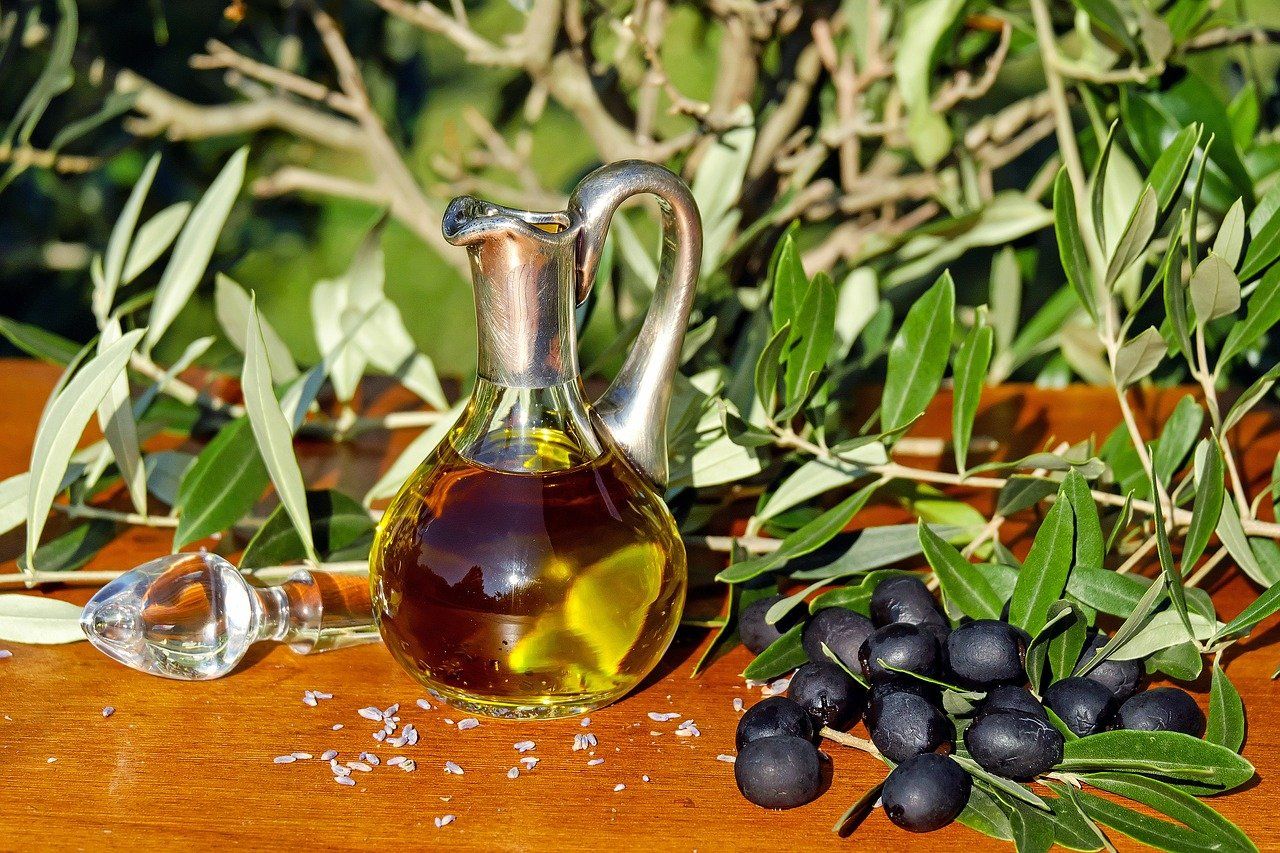 Un frasco de aceite de oliva acompañado de unas aceitunas negras / Pixabay