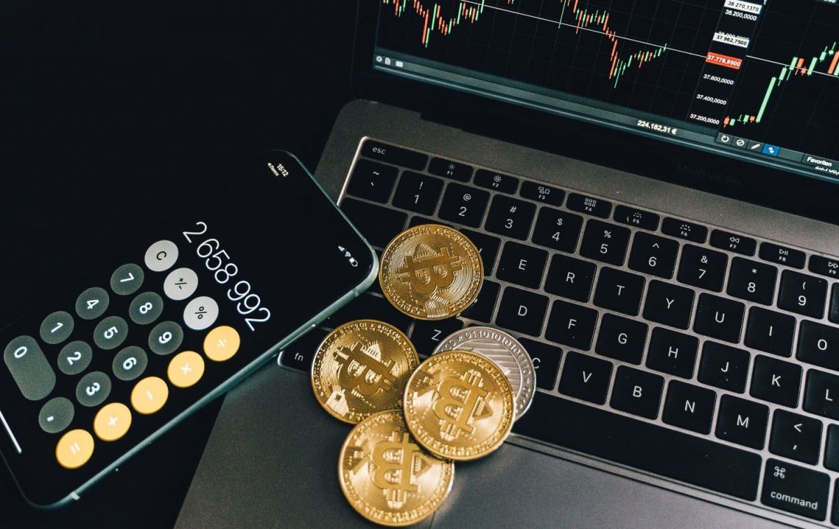 Varias monedas bitcoin junto con una calculadora y un portátil / PEXELS