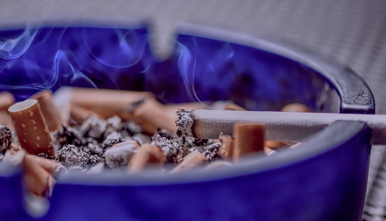 Un cenicero lleno de tabaco, con un cigarro encendido y colillas apagadas / PIXABAY