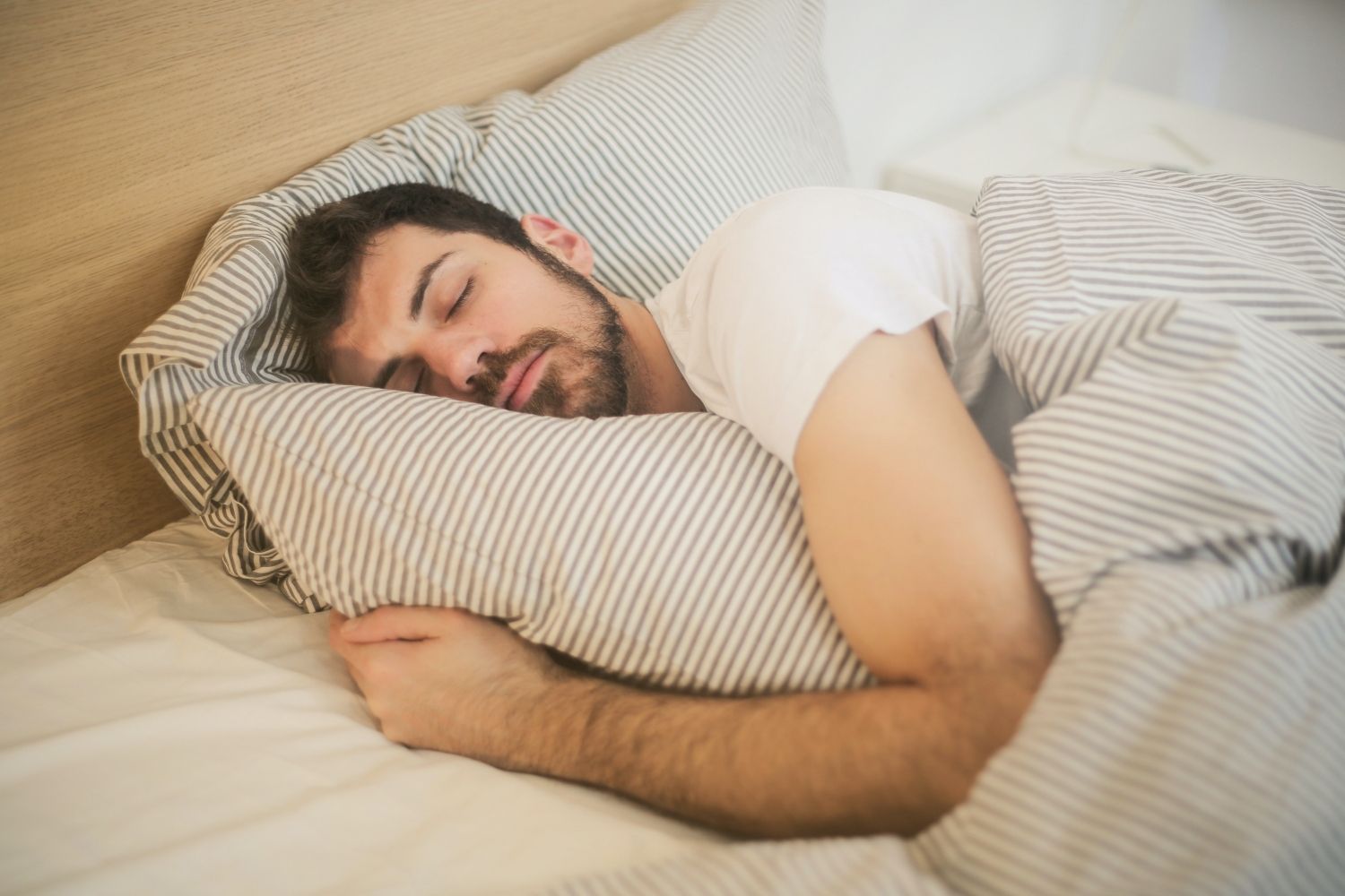 Un hombre que ronca duerme en una cama / PEXELS