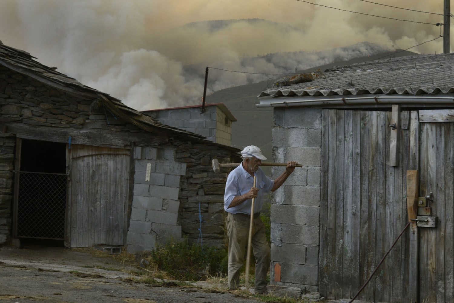 Un hombre con un incendio activo al fondo en la aldea de As Taboazas (Ourense) / EP