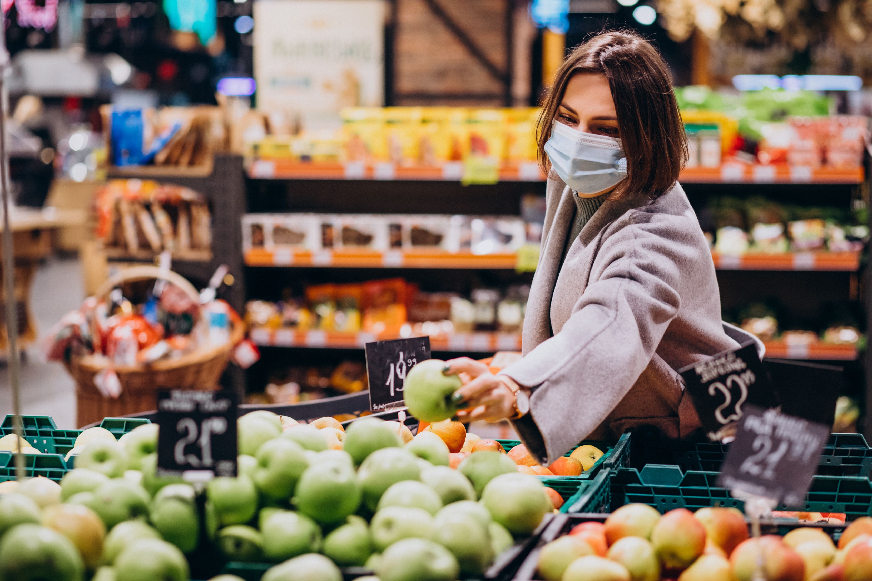 Una mujer con una mascarilla mientras hace la compra / FREEPIK