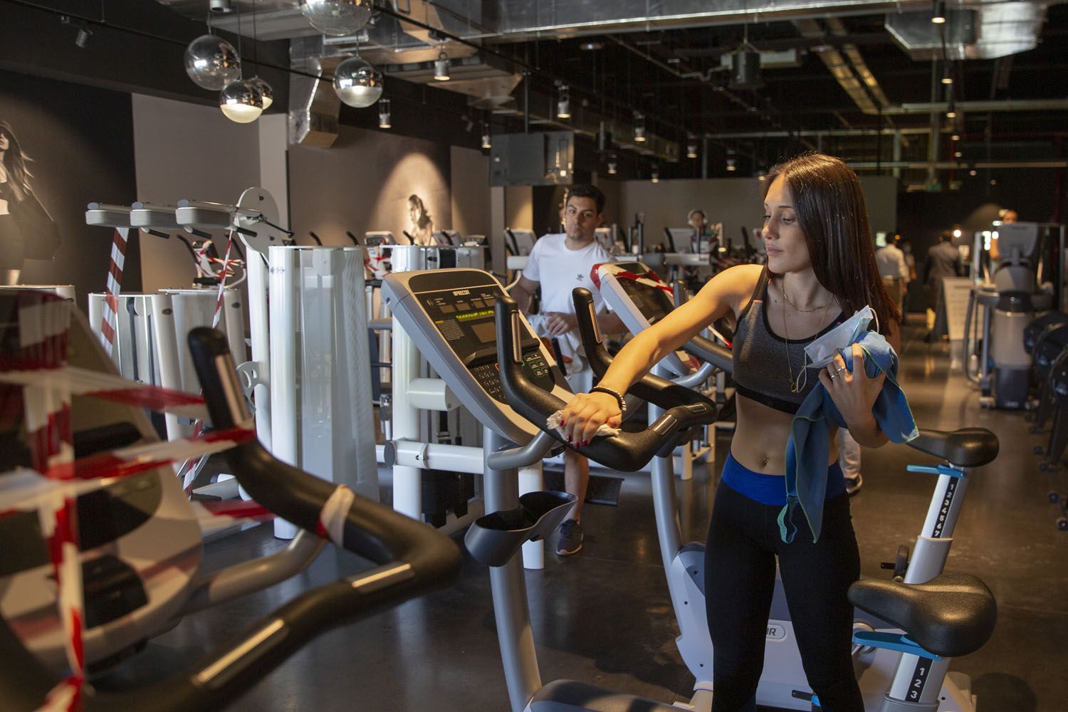 Una usuaria limpia una máquina tras hacer ejercicio en un gimnasio McFit / EP