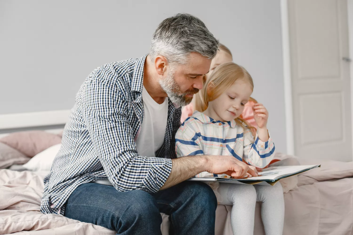 Un padre lee a su hija un cuento / FREEPIK