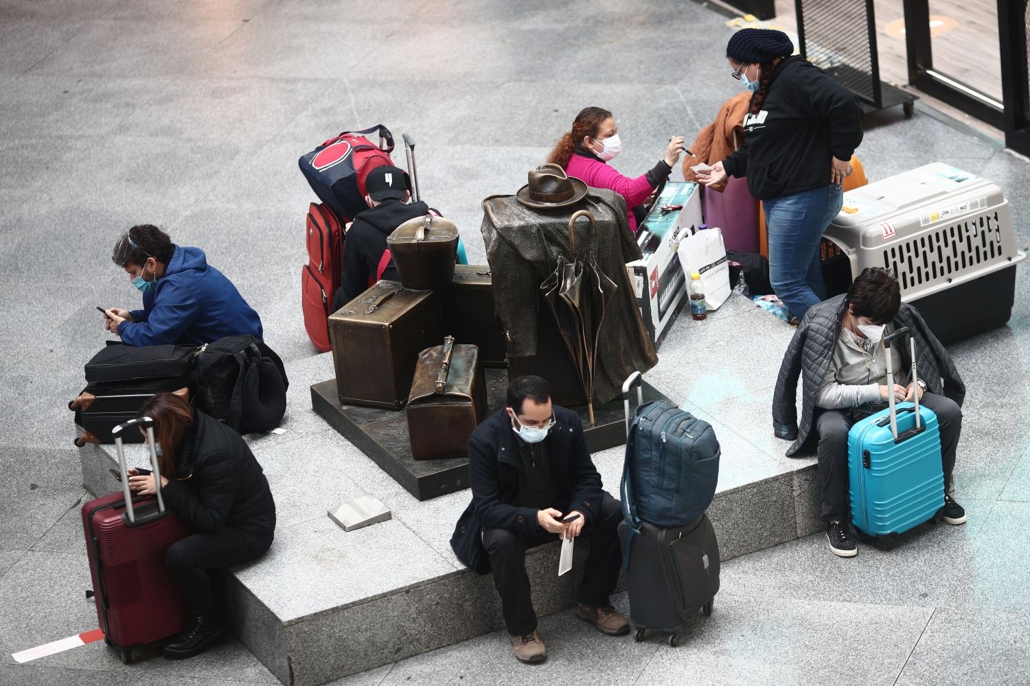 Varios viajeros españoles esperan en un asiento de la estación de tren de Atocha / EP