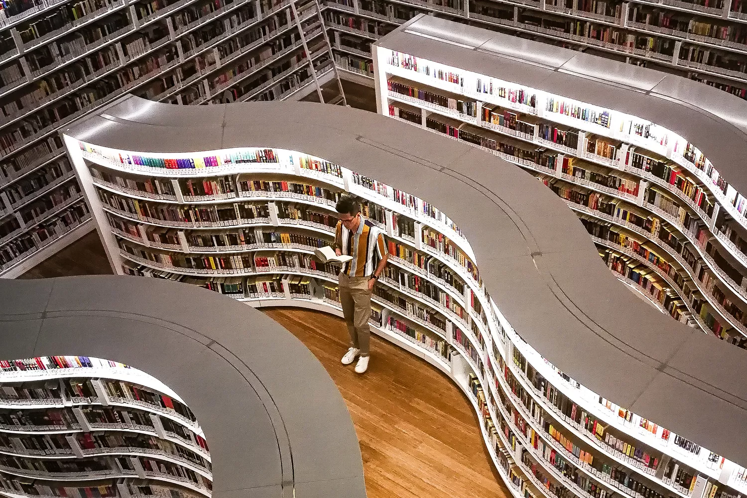 Un hombre rodeado de estanterías con libros / PEXELS