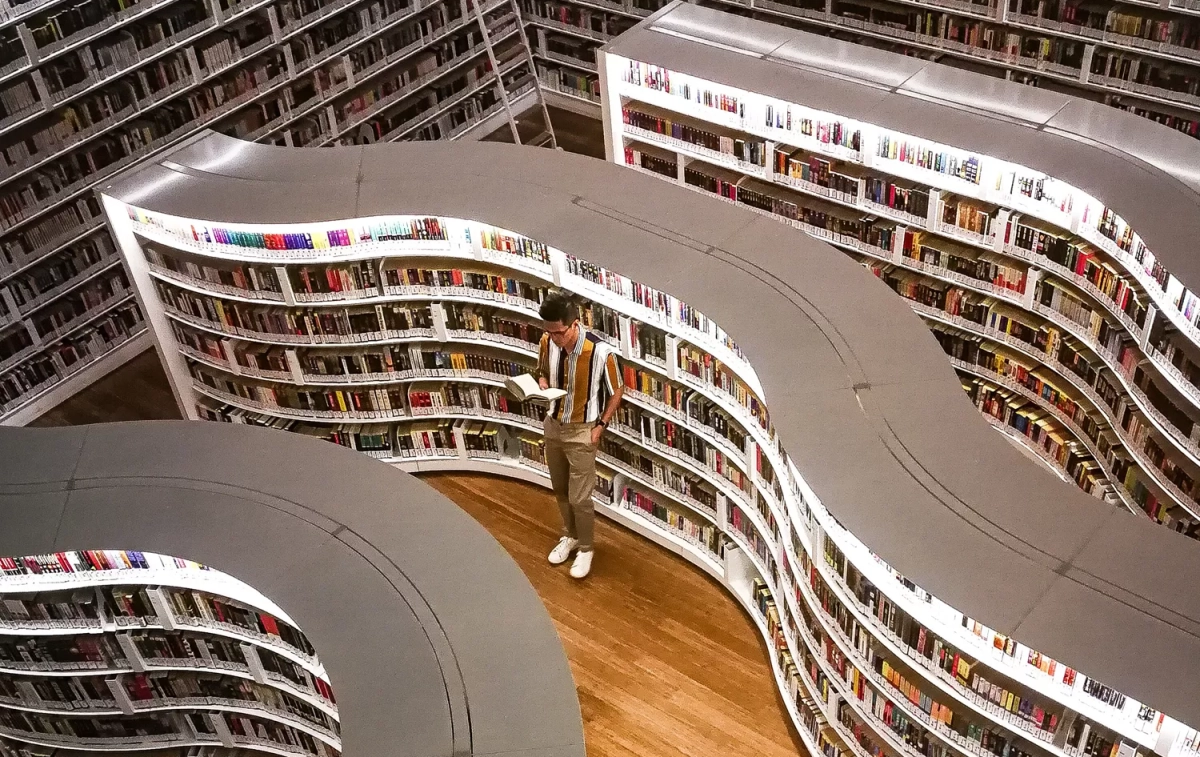 Un hombre rodeado de estanterías con libros / PEXELS Un hombre rodeado de estanterías con libros / PEXELS