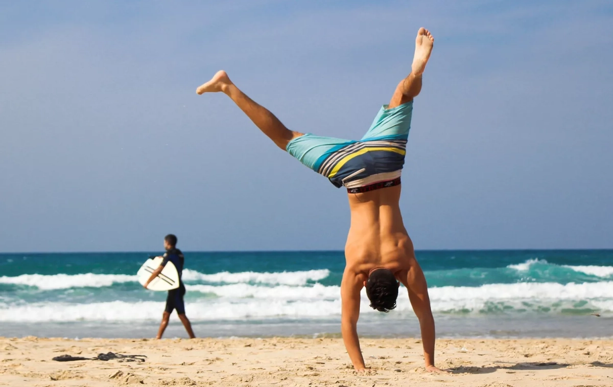 Un hombre boca abajo en la playa / PEXELS