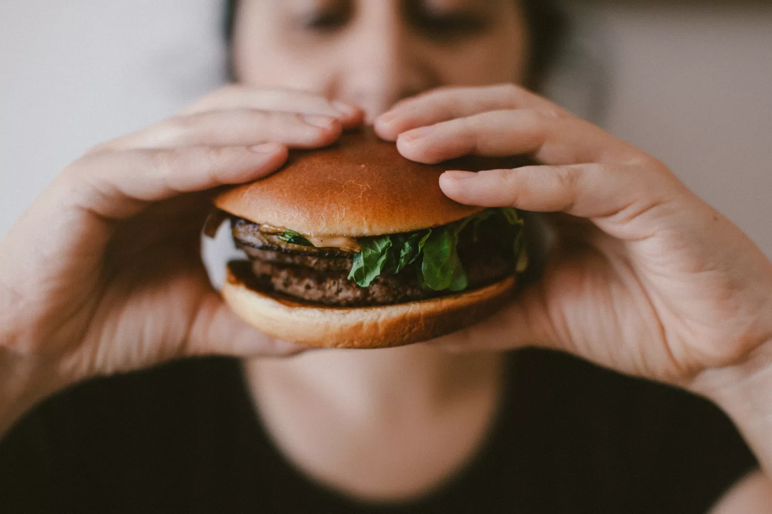 Una persona sostiene una cheesburger / UNSPLASH