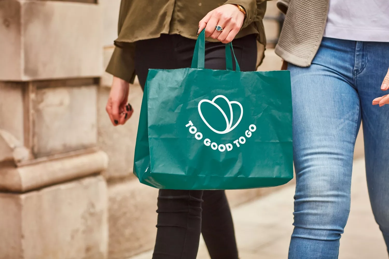 Dos personas llevan una bolsa de papel de Too Good To Go / TOO GOOD TO GO