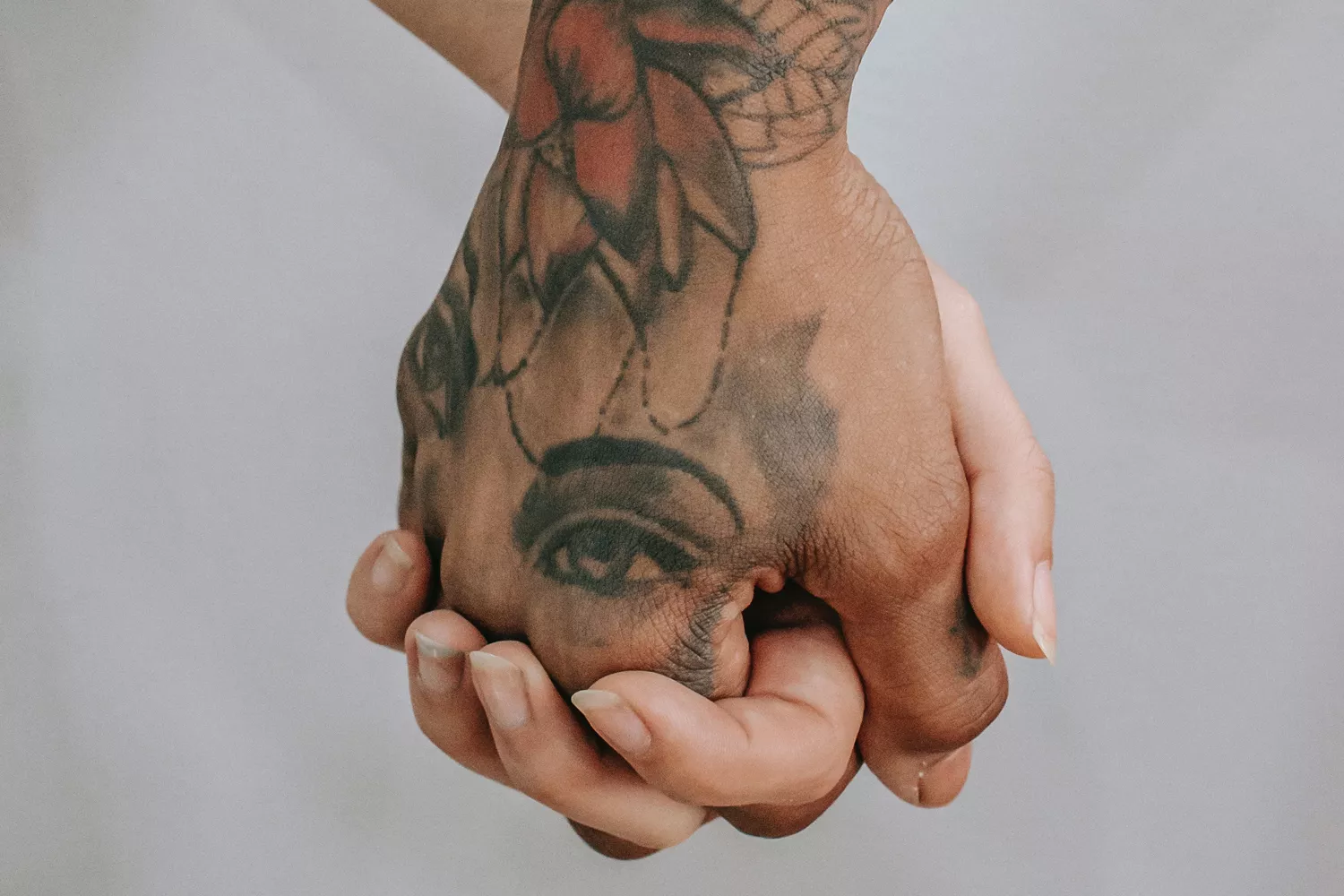 Dos manos entrelazadas, una de ellas con tatuajes / PEXELS