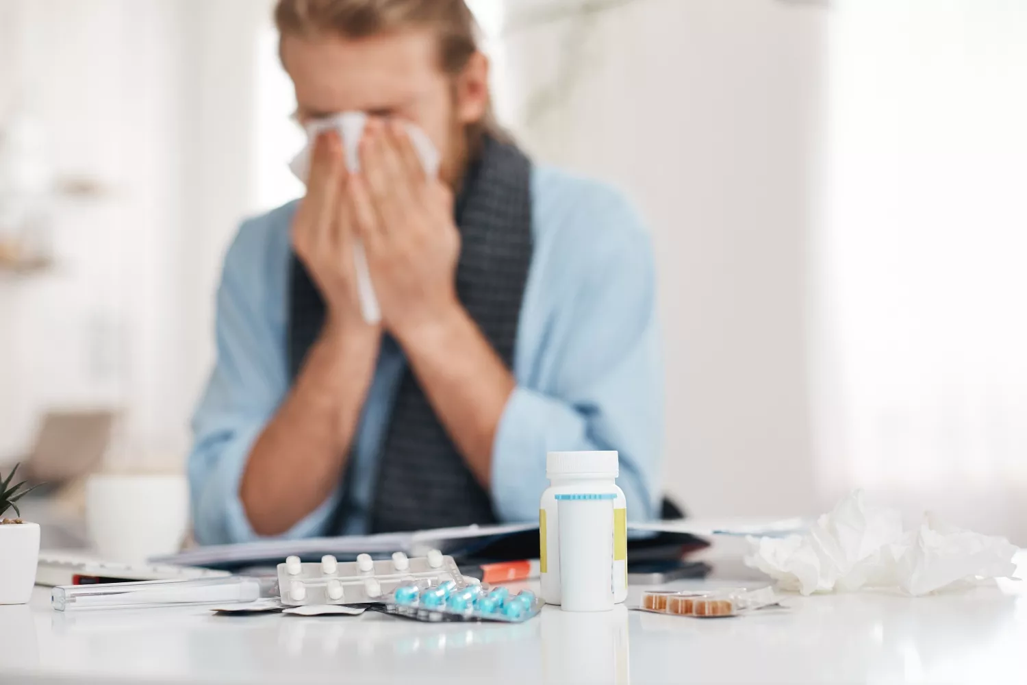 Un hombre resfriado con varios medicamentos / FREEPIK