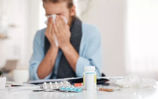 Un hombre resfriado con varios medicamentos / FREEPIK