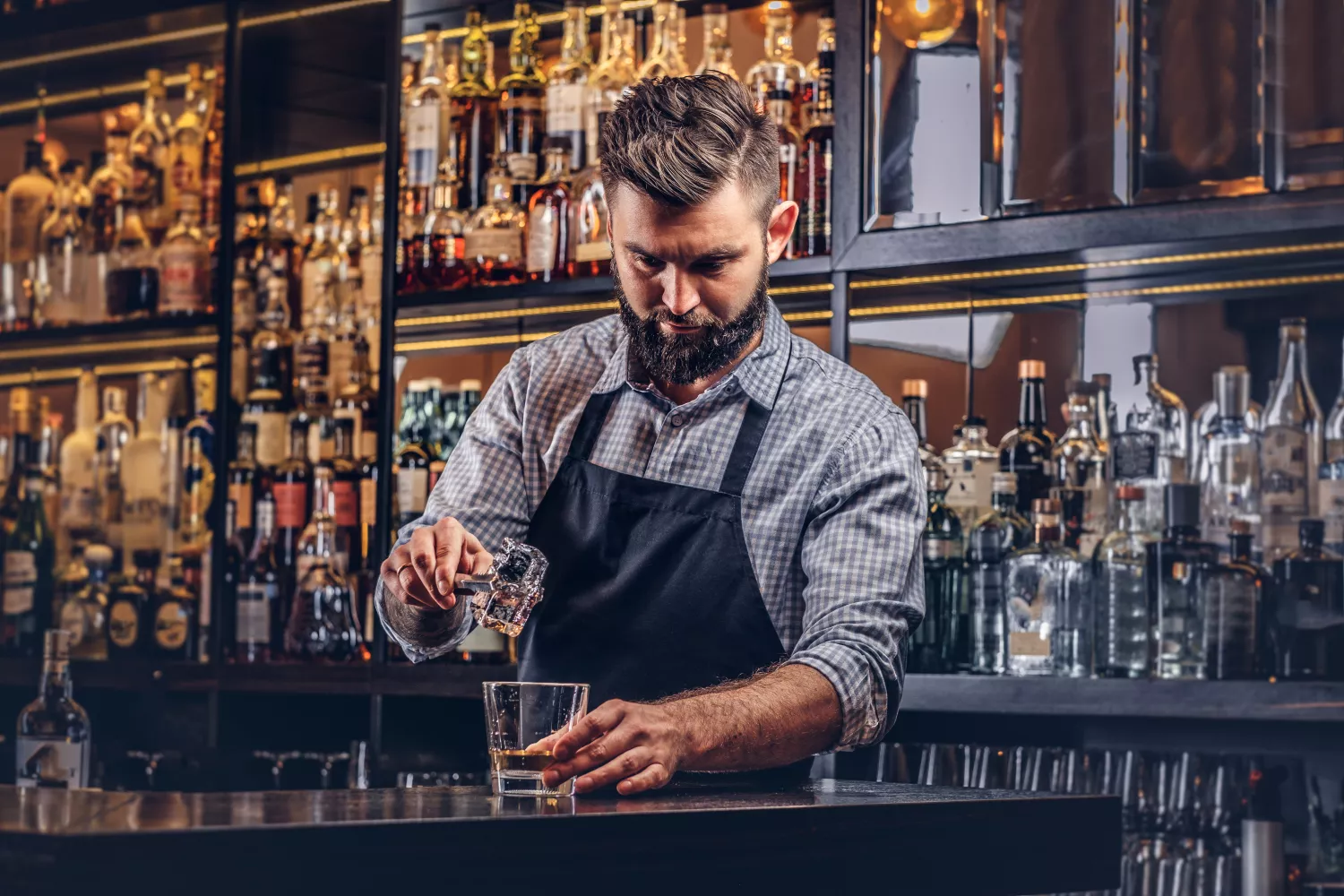 Un barman prepara un cóctel con diferentes licores / FREEPIK