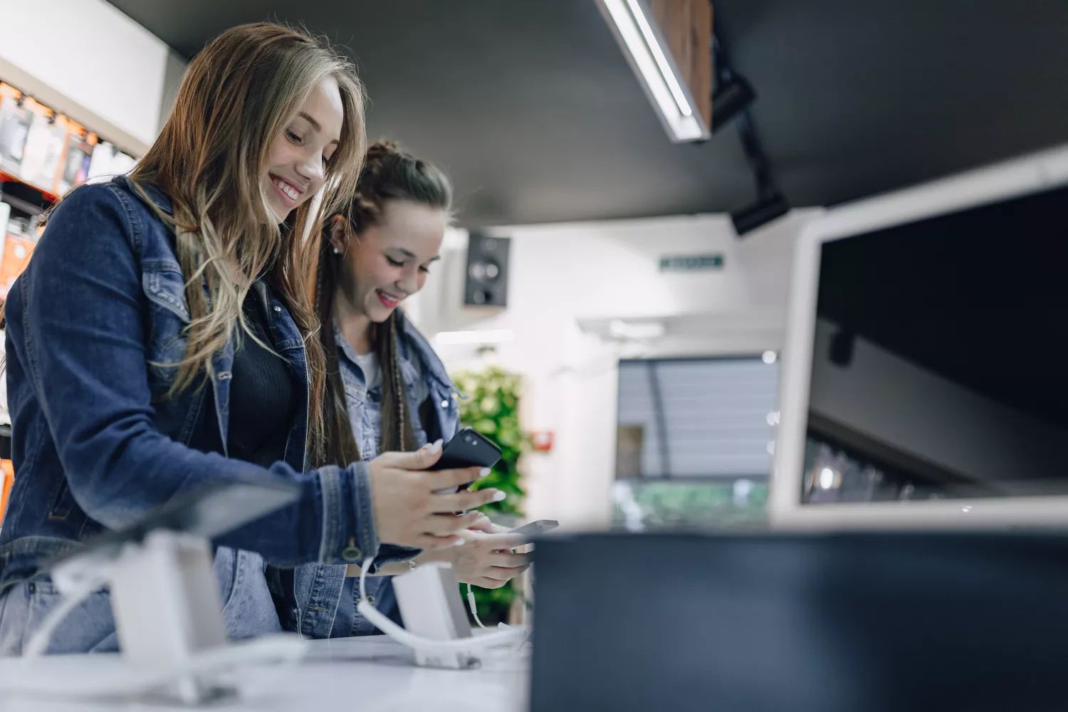 Dos chicas miran móviles en un Cash Converters / FREEPIK - @pressahotkey