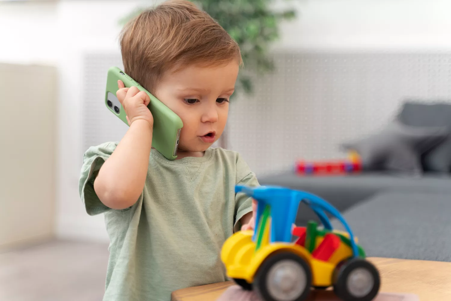 Un niño con juguetes infantiles y un móvil / FREEPIK