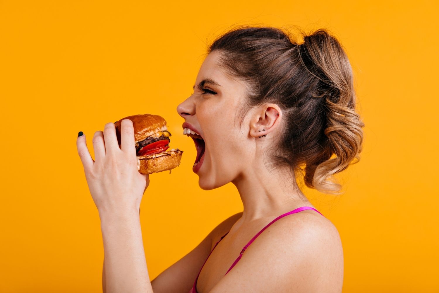 Una chica a punto de comerse una hamburguesa / FREEPIK 