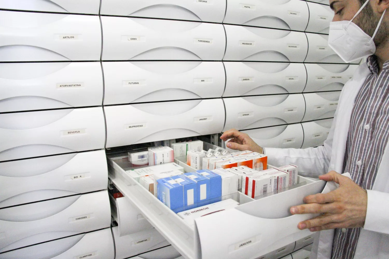 Un farmacéutico abre una estantería con medicamentos / LUDA