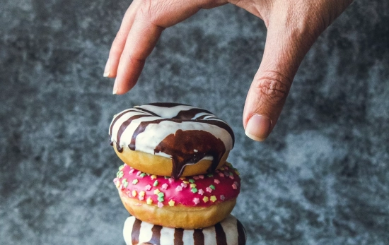 Una persona acerca su mano a unos dulces repletos de azúcar / PEXELS