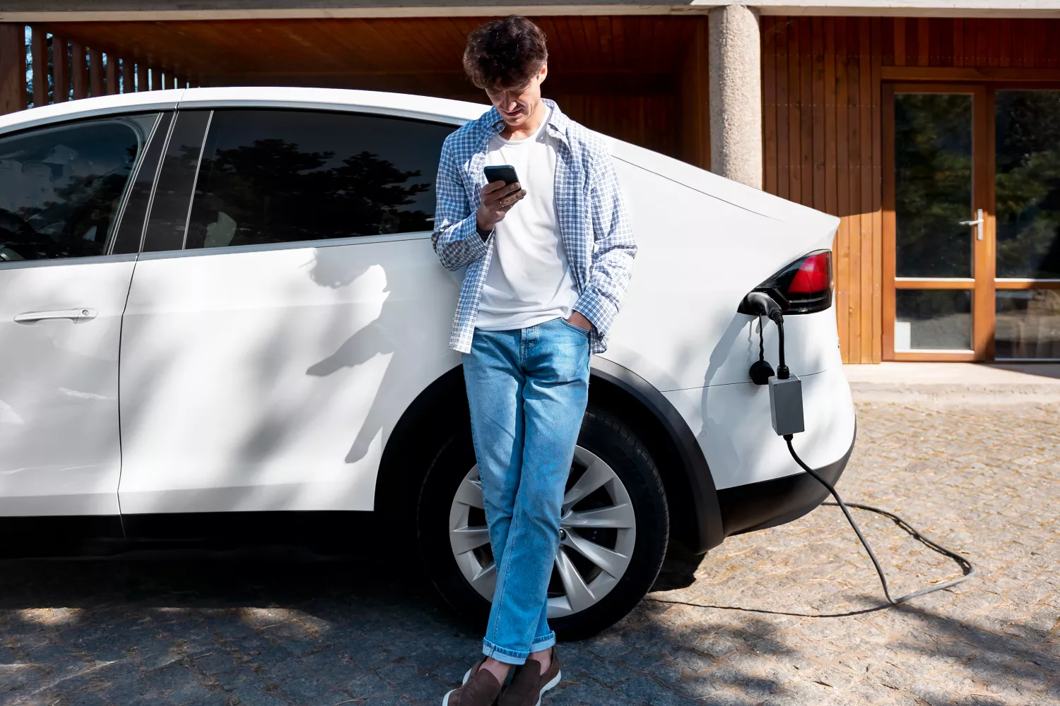 Una persona espera a que se cargue su coche eléctrico / FREEPIK