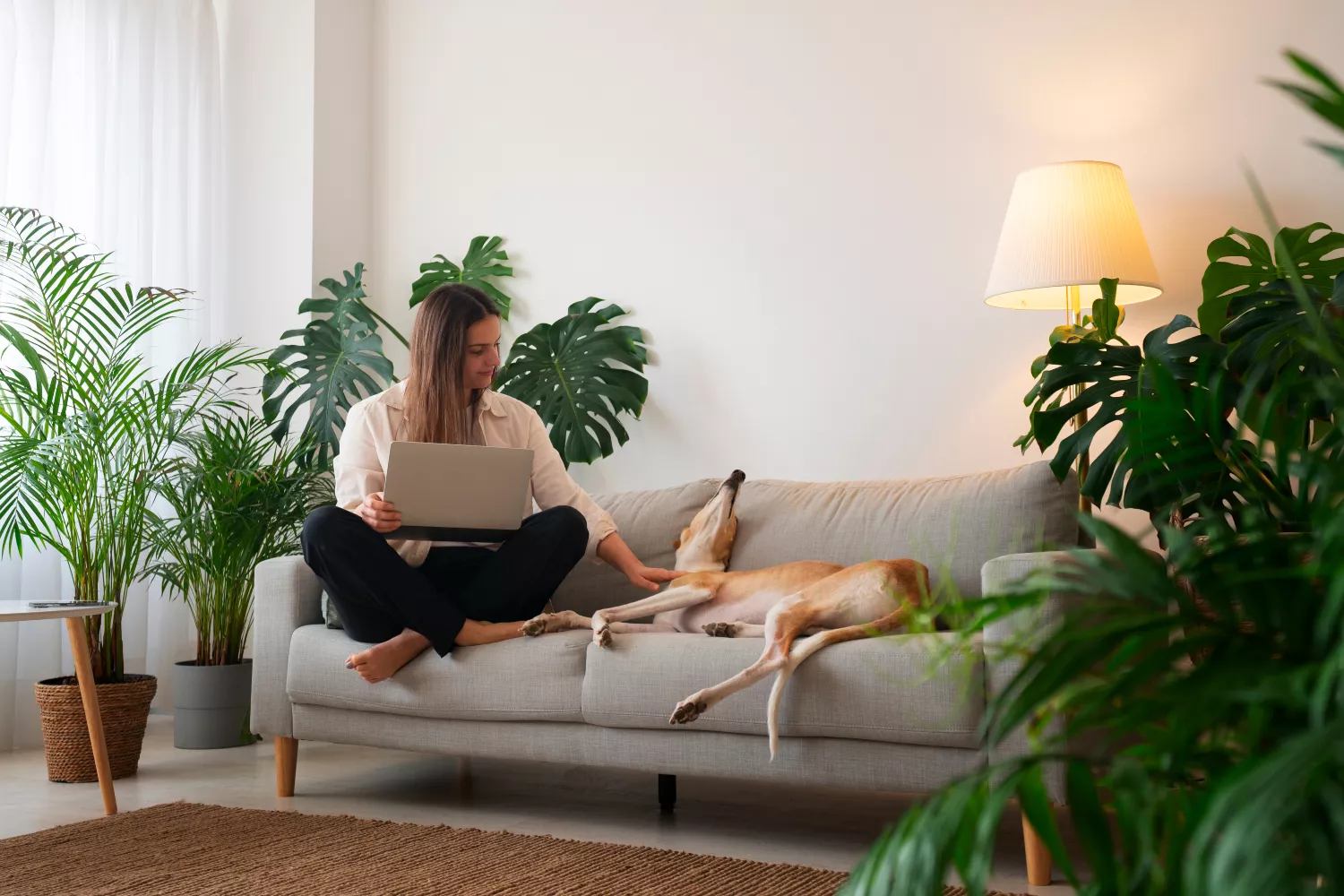 Una persona junto a su perro en el sofá, en un salón con ambientador de Zara Home / FREEPIK