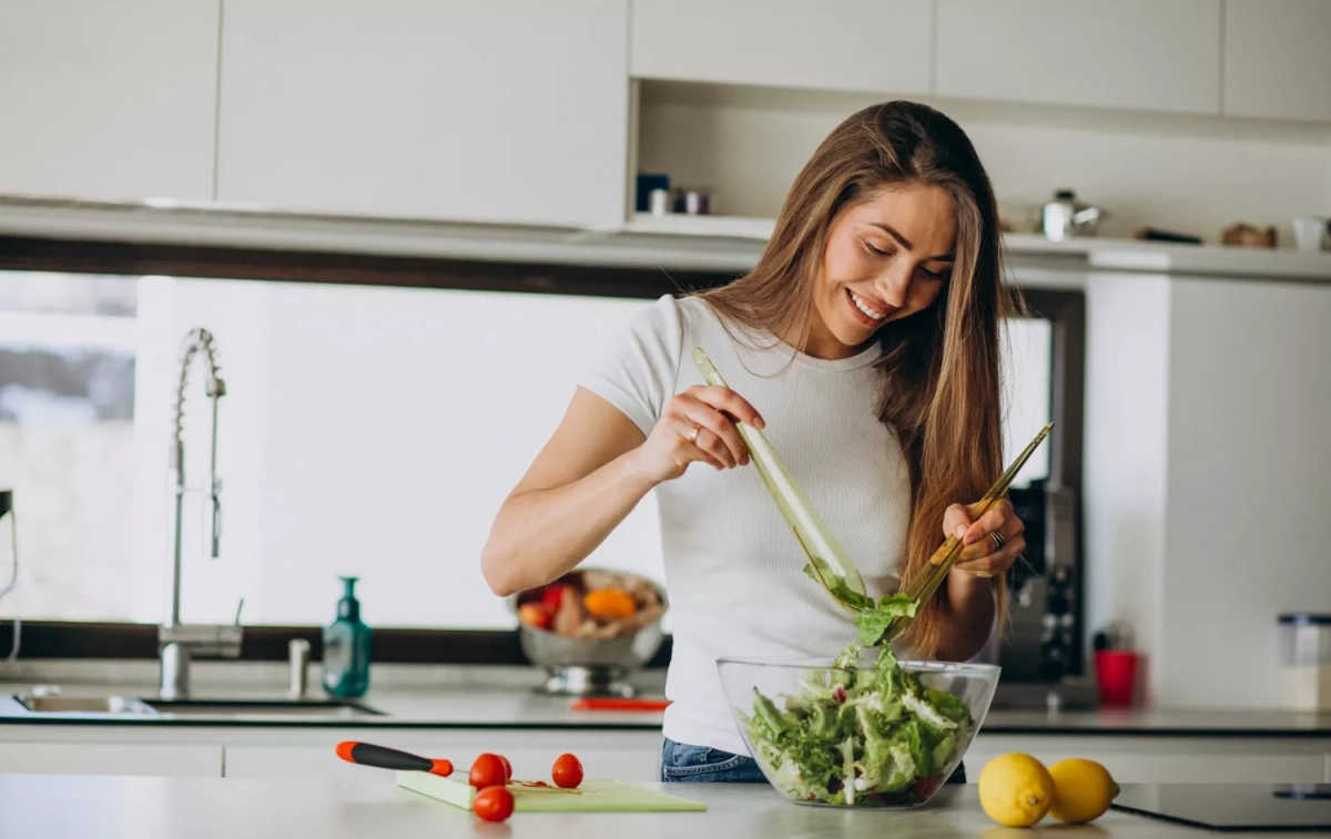 Una mujer que vive en la ciudad prepara una ensalada saludable / FREEPIK - @senivpetro