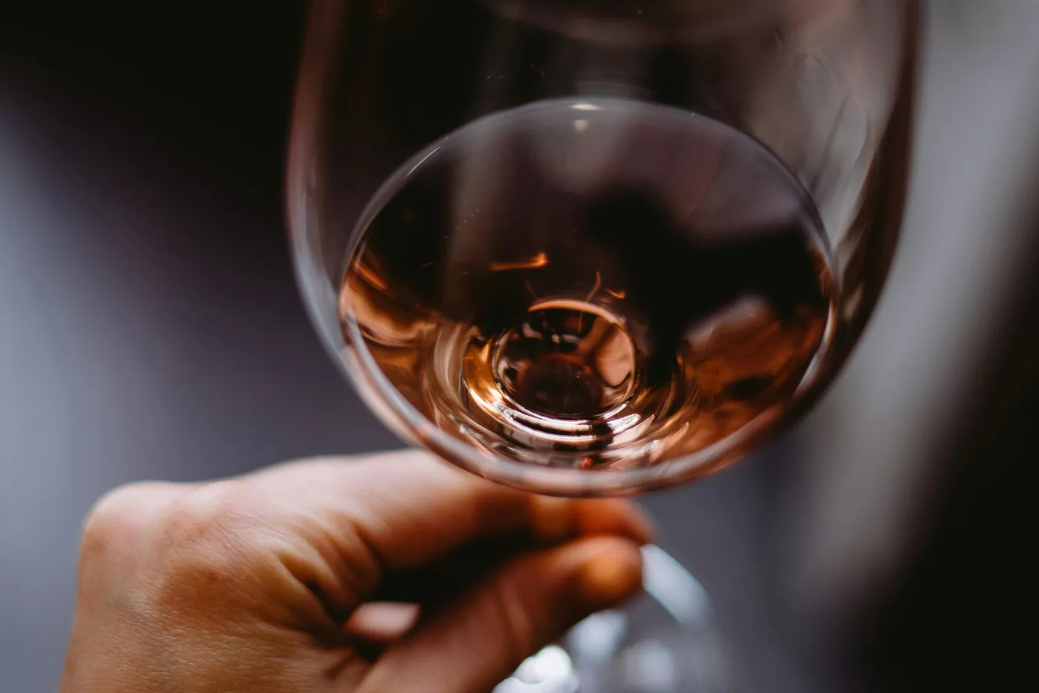 Una persona sostiene una copa de vino rosado / PEXELS