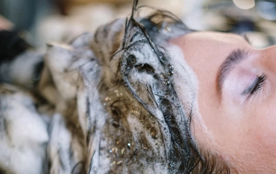 Una persona se limpia el cabello con uno de los champús de Mercadona/ PEXELS