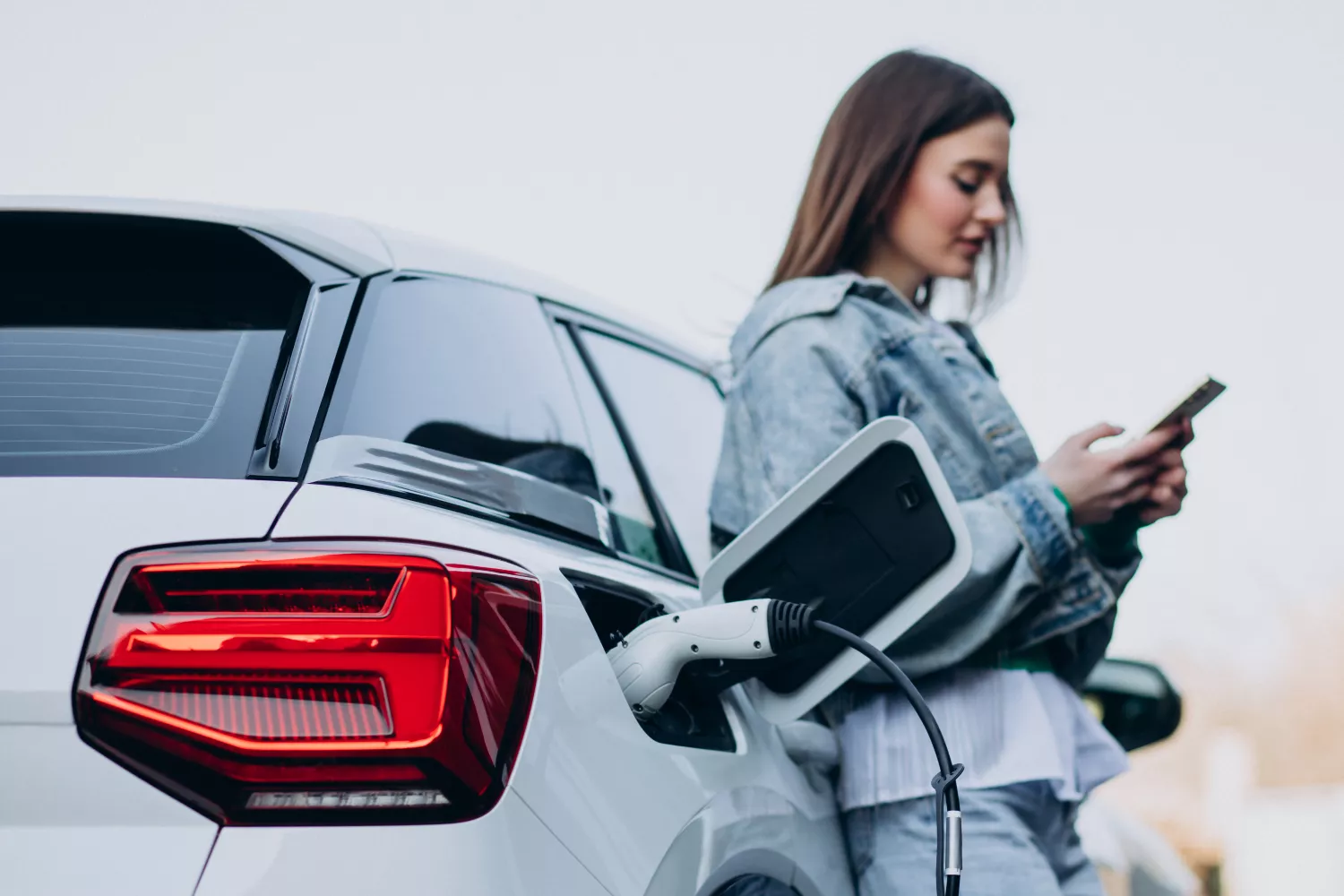 Una chica carga su coche eléctrico / FREEPIK - senivpetro