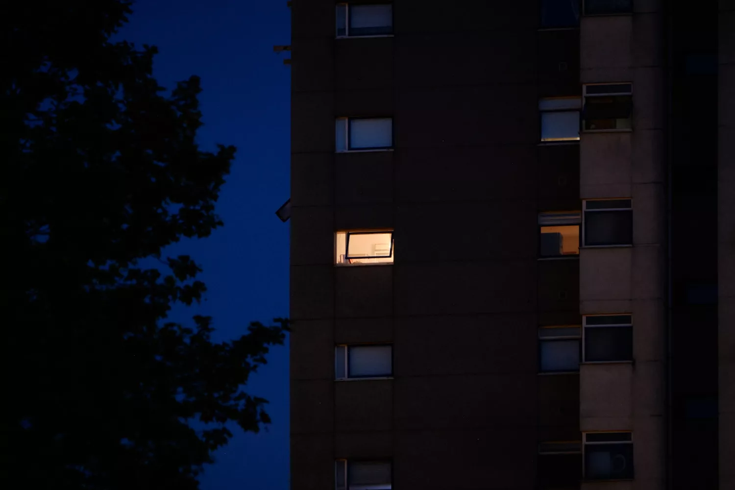 Una ventana con una luz encendida en un edificio con familias que se acogen al bono social eléctrico / Agostime - EP