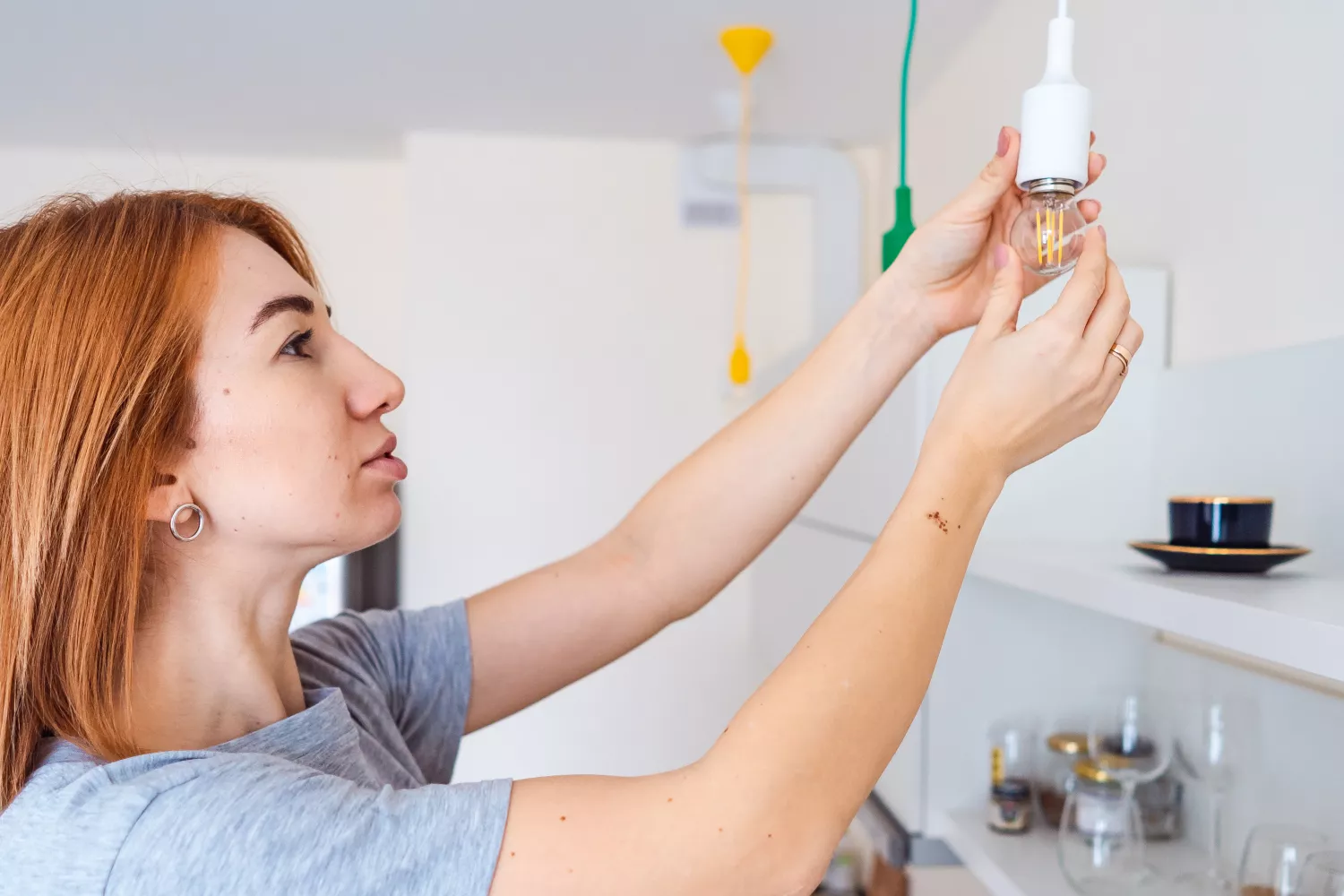 Una mujer instala una bombilla de bajo consumo para ahorrar en la factura de la luz / FREEPIK  - @teksomolika