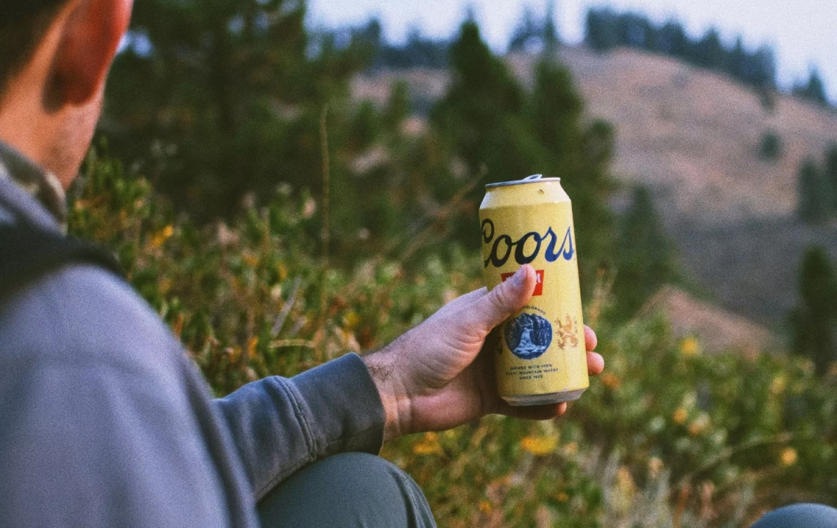 Una persona con una cerveza Coors / UNSPLASH