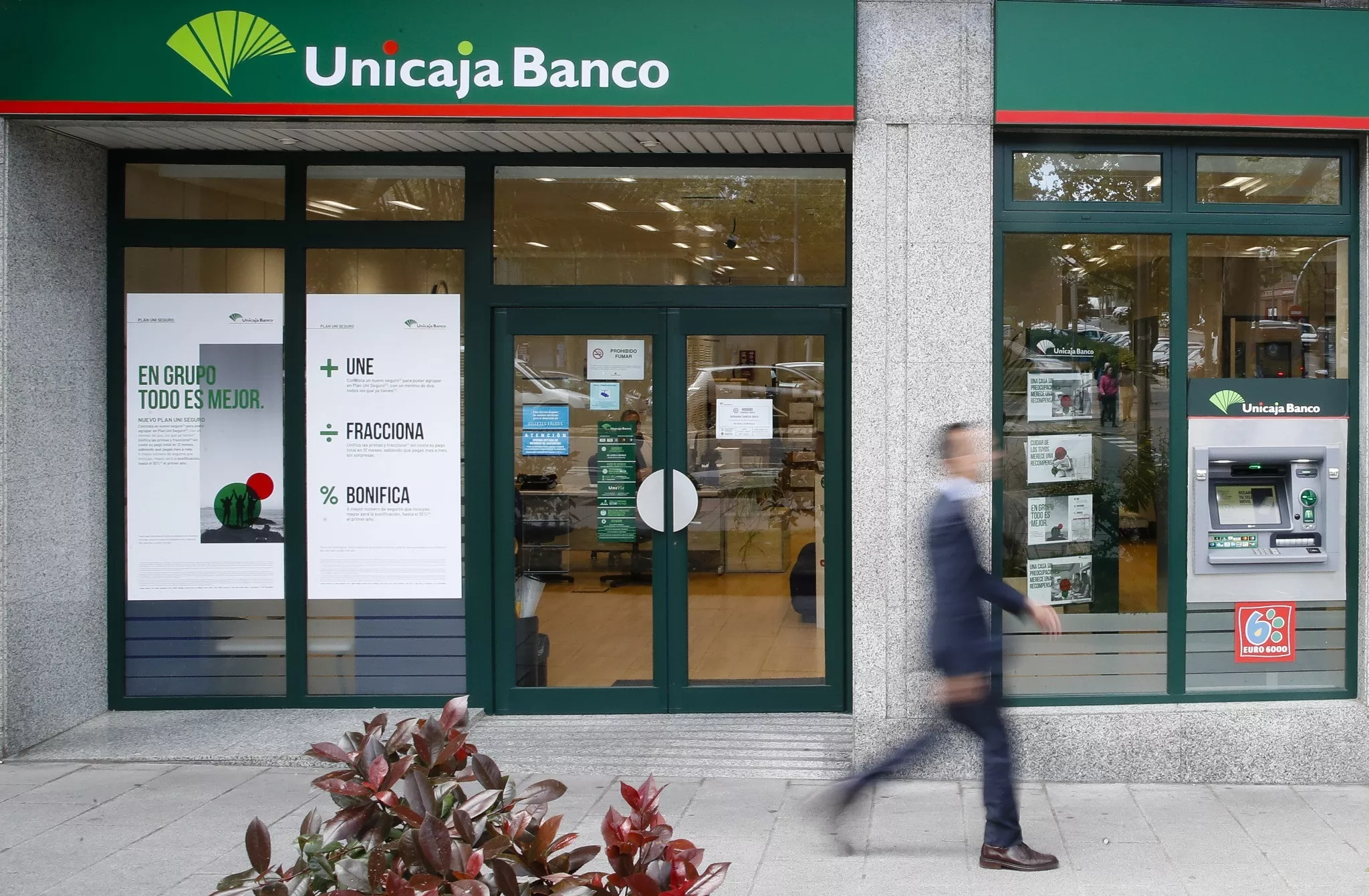 Una persona pasa delante de una oficina de Unicaja / EP - UNICAJA