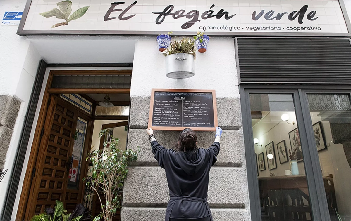 Una trabajadora coloca el menú del día en el restaurante El fogón verde / ELFOGÓNVERDE