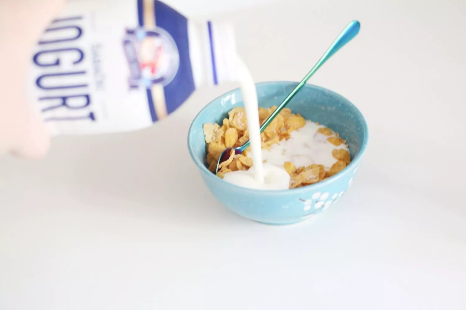 Una persona añade yogur a su bol de cereales / PEXELS