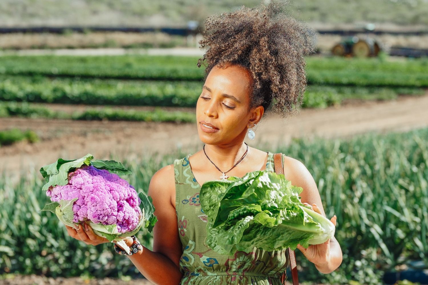 Una mujer con dos hortalizas, alimentos que contienen proteína vegetal / PEXELS