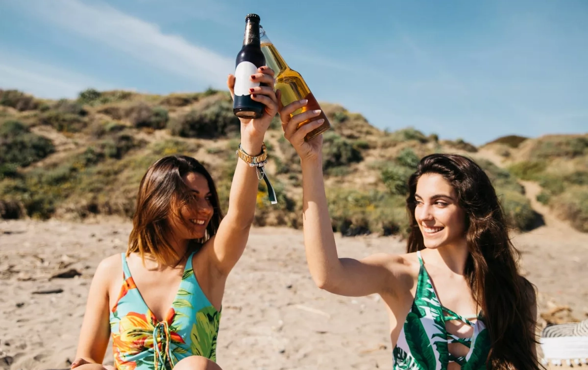 Dos chicas toman una playa en una cerveza / FREEPIK