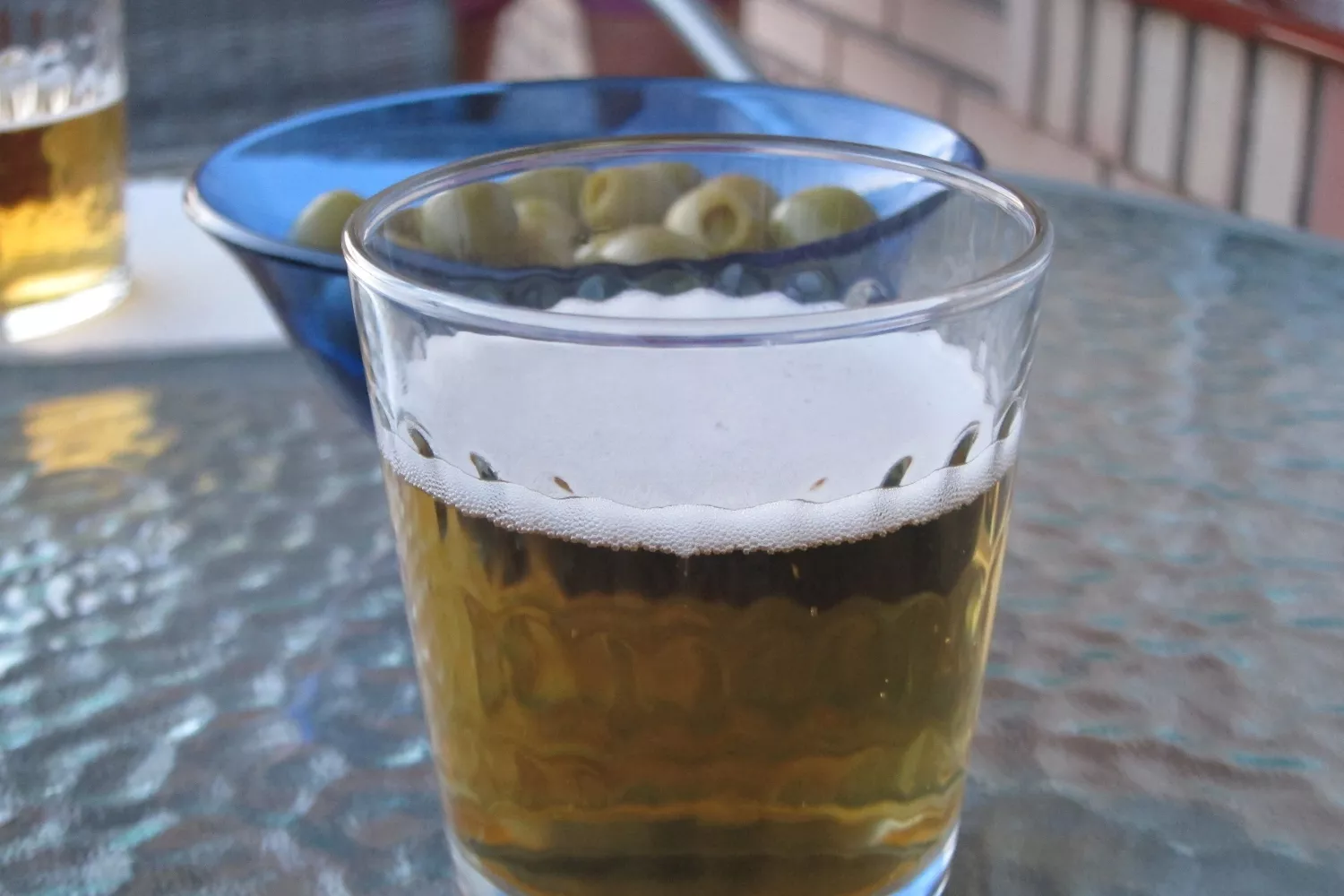 Una caña de cerveza junto a una tapa de aceitunas en un bar / EP