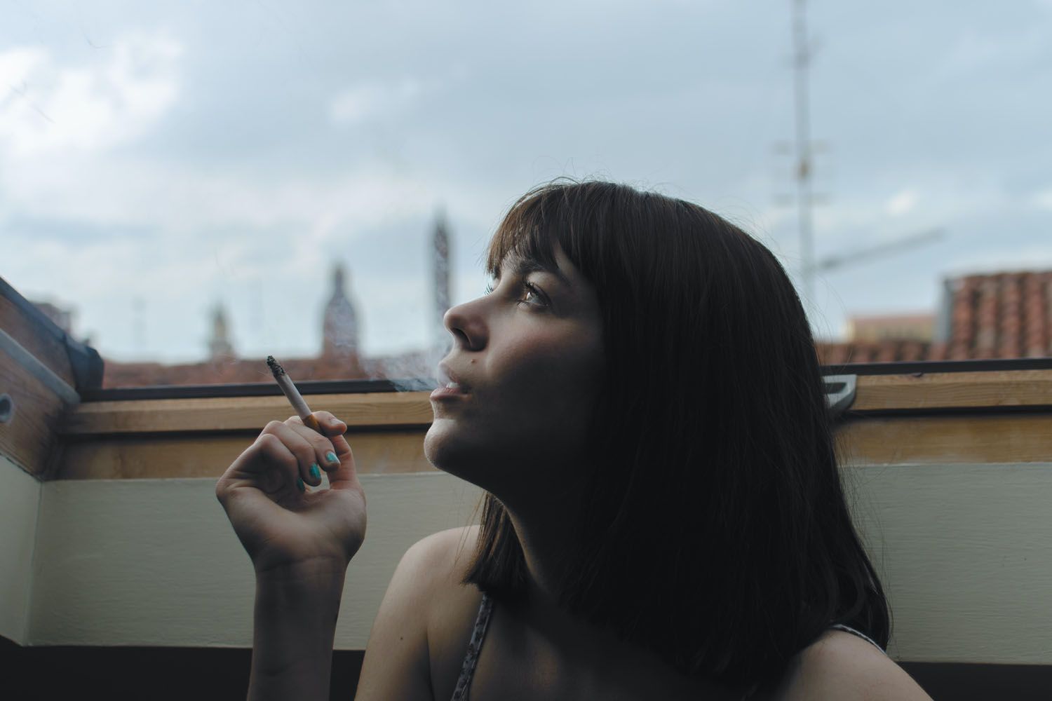 Una mujer fuma un cigarrillo con nicotina con la ventana abierta / EP