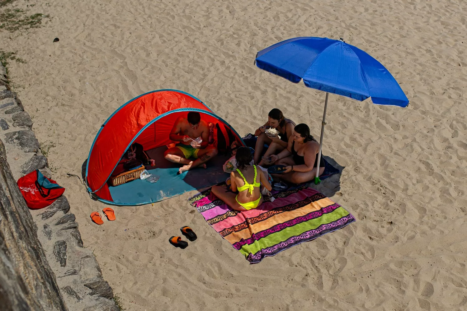 Un grupo de amigos come en la playa mientras se protegen del sol y la arena / ELENA FERNÁNDEZ - EP