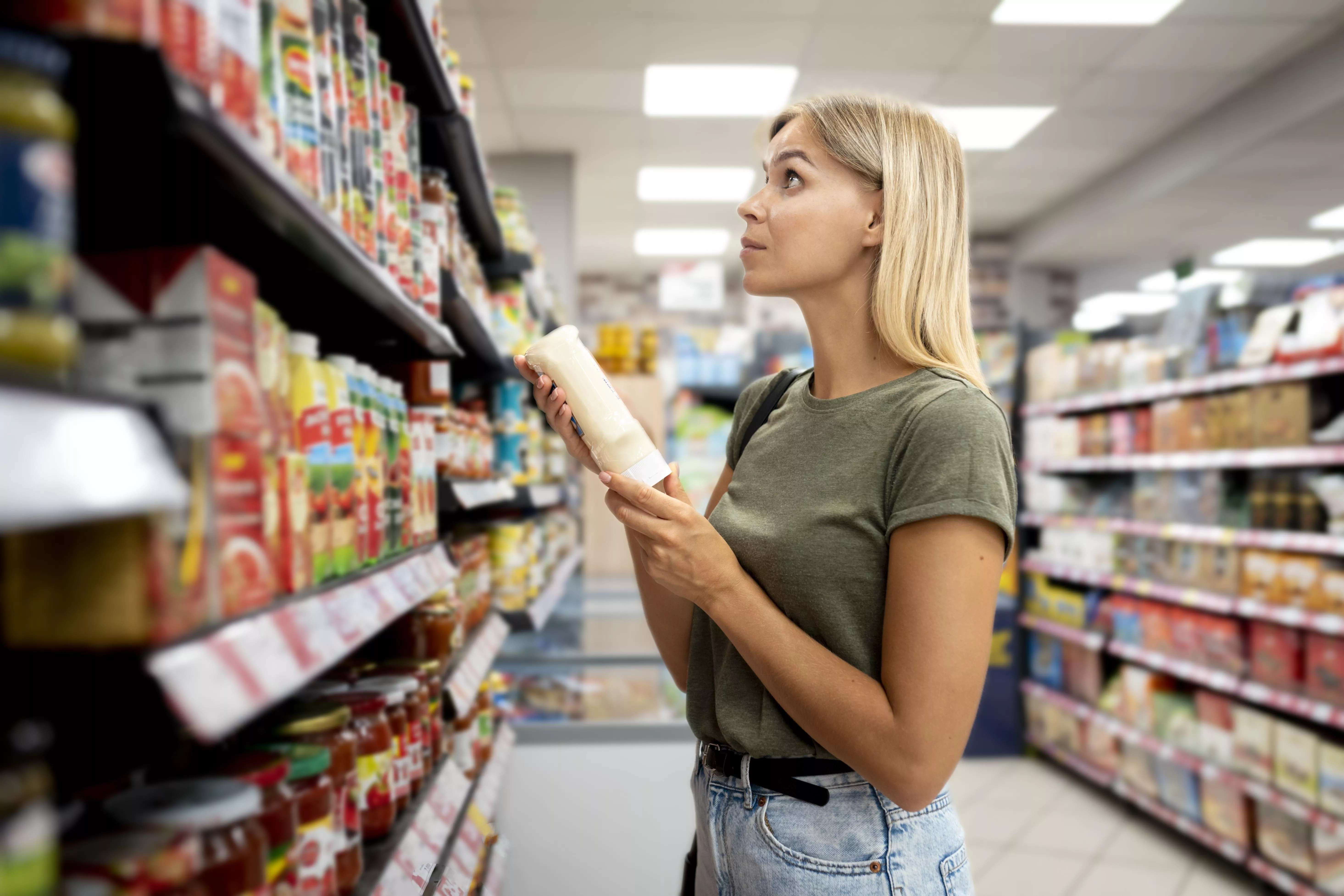 Una mujer comprueba en el supermercado qué productos han subido más de precio / FREEPIK