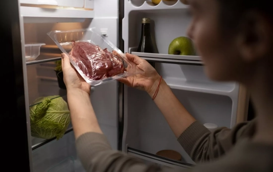 Una persona guarda carne en la nevera / FREEPIK