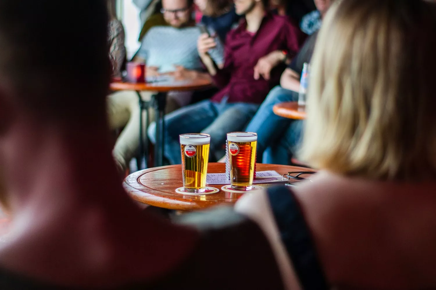 Varias personas en un bar beben cerveza / UNSPLASH