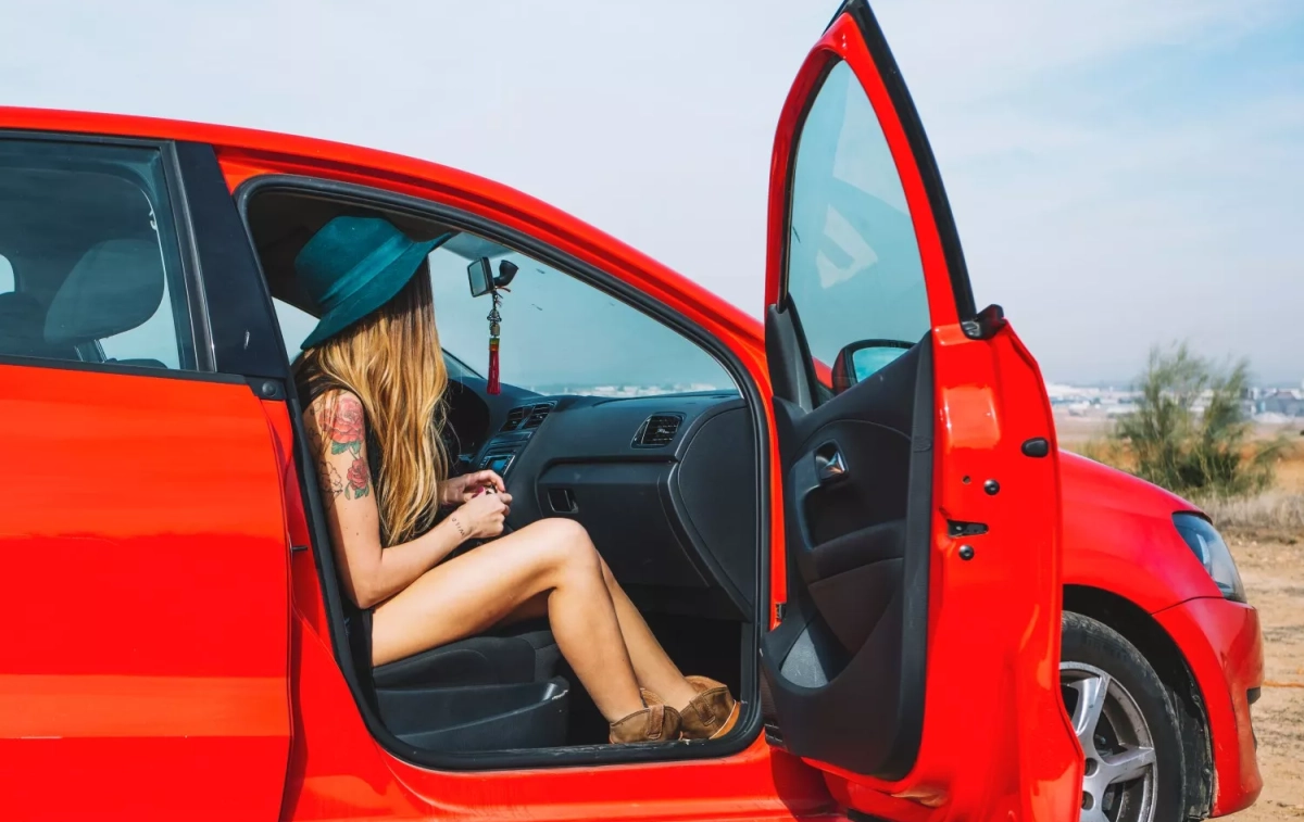 Una mujer en un coche rojo / FREEPIK