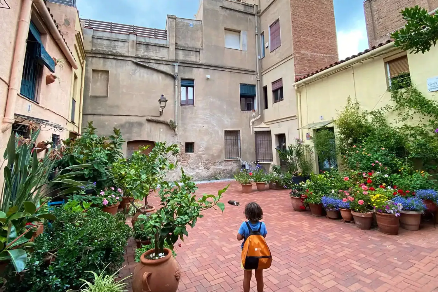 Un niño en una pequeña plaza con casas que tienen plantas en la puerta para enfriar el hogar / Carlos Márquez Daniel