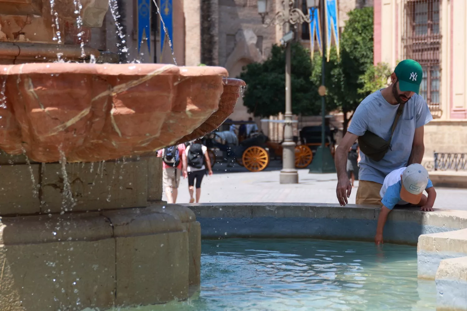 Una famlilia se refresca en una fuente en Sevilla para soportar las altas temperaturas y prevenir un golpe de calor / ROCÍO RUZ - EP