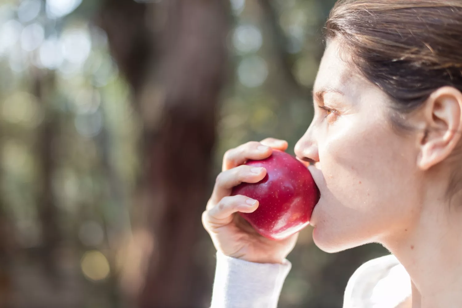 Una persona muerde una manzana, uno de los alimentos que ayudan a mantener un corazón sano / FREEPIK