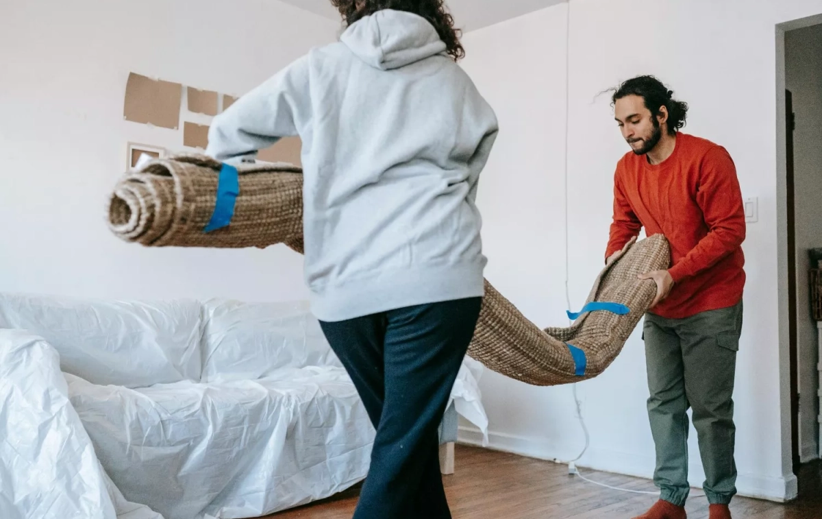 Dos personas colocan su alfombra en un piso de alquiler / PEXELS